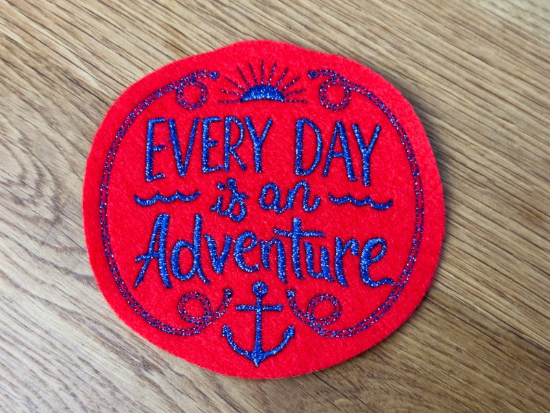 Roter Patch mit blauem Schriftzug Every Day is an Adventure